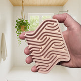 Hand holding a pink, wavy-patterned object with a minimalistic room in the background